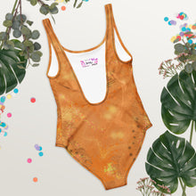 Load image into Gallery viewer, Orange swimsuit with a brand logo on a light gray background with decorative elements.