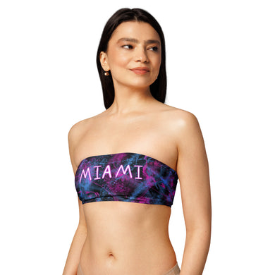 Woman wearing a strapless bikini top with 'MIAMI' print on a white background. Purple, pink, blue and black bikini top.