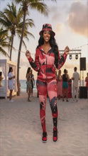 Cargar y reproducir el video en el visor de la galería, Woman on the Beach with a red and black outfit. Hat, sweater and leggings of a flower with drips.
